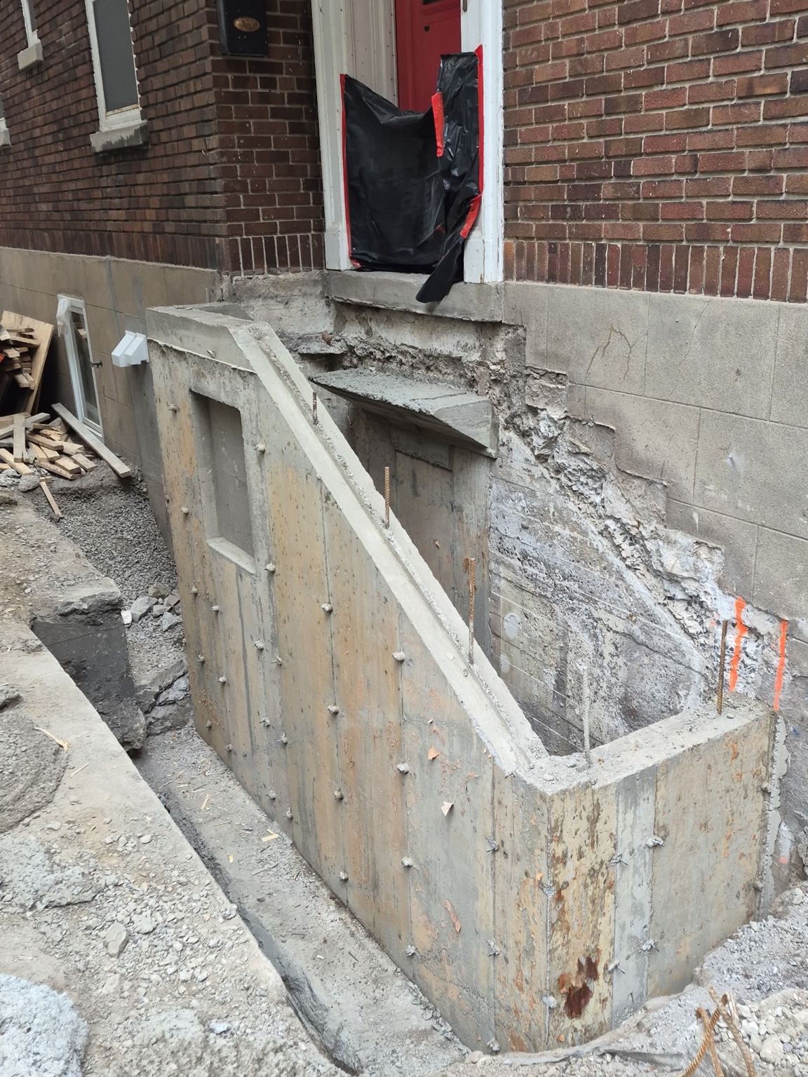 Ancien accès latéral pendant la démolition, avec l’escalier retiré et le mur de fondation dégagé