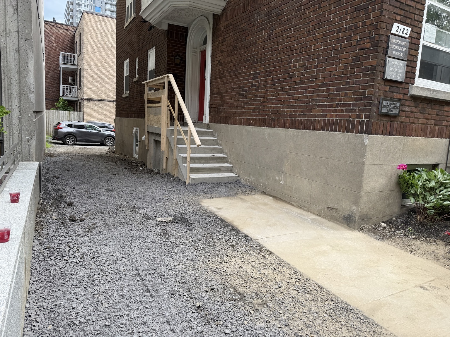 Accès latéral après reconstruction de l’escalier et du palier en béton, avec une rampe de bois en place
