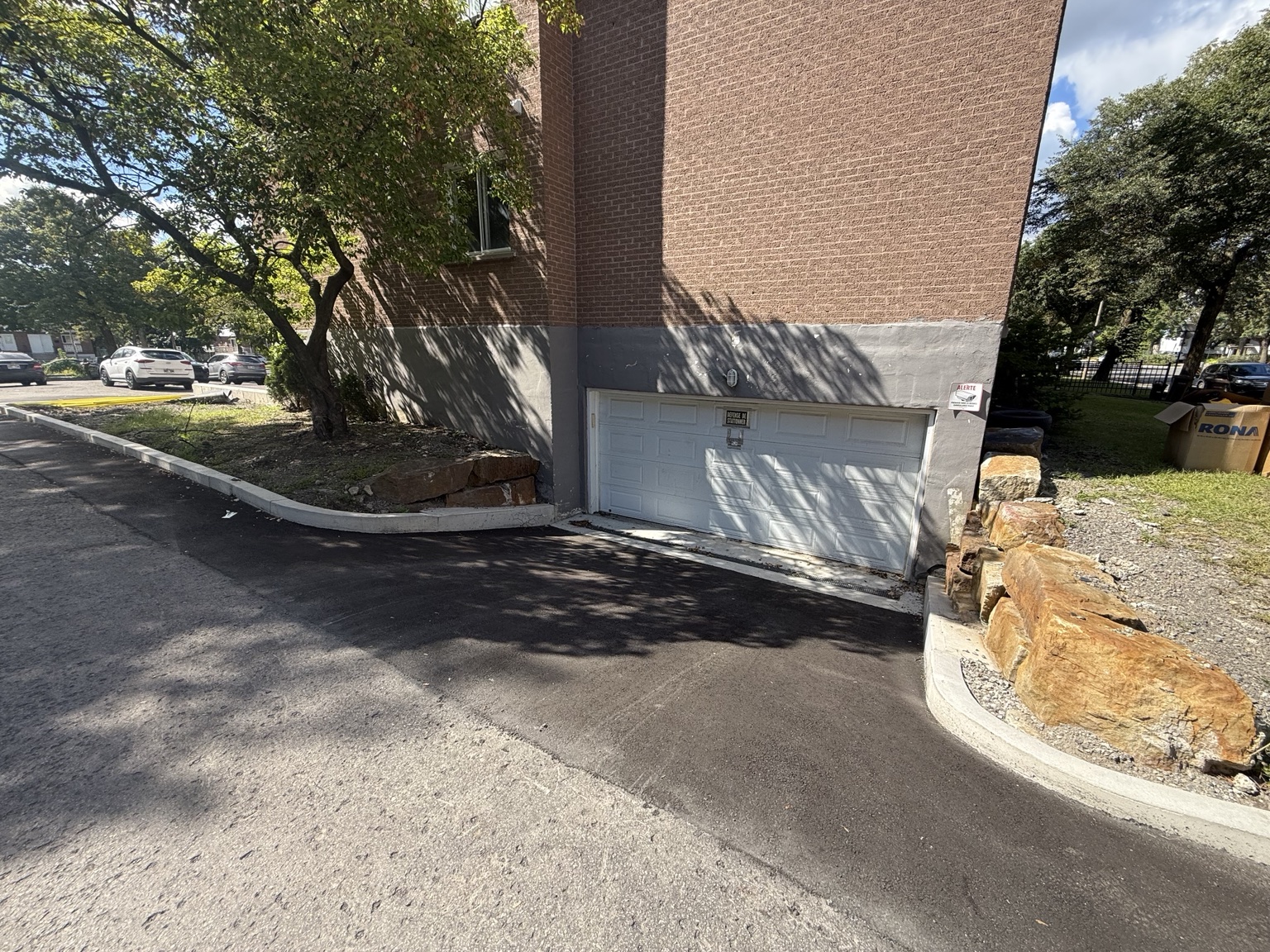 Bordures de béton courbes et pavage à l’entrée d’un garage d’immeuble à logements à Rivière-des-Prairies